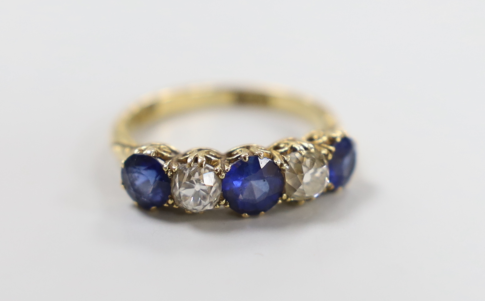 An 18ct gold, three stone blue paste and two stone diamond set half hoop ring
